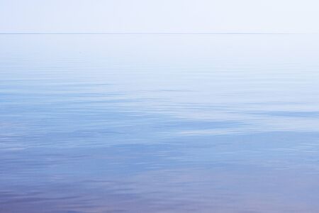 The surface of a blue sea, a river without waves under a clear blue sky. water surface with sun raysの写真素材