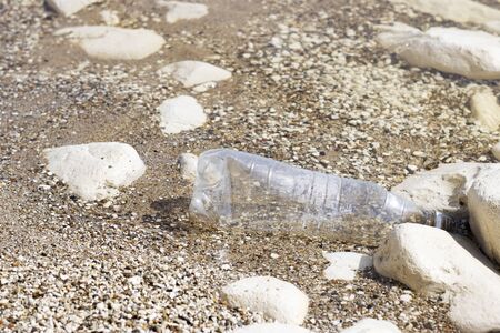 plastic bottle on the rocky Bank of the river, sea. concept of pollution of rivers, seas and oceans. refusing to use plasticの写真素材