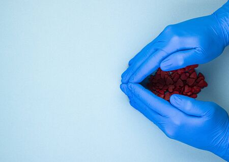 hands in medical gloves cover a lot of small red hearts. the concept of protecting the lives of many people by doctors. fighting for the life of every patientの写真素材