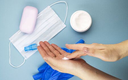 women's medical hands take care of the skin of their hands after removing gloves, top view. moisturizing and nourishing cream for hands damaged by antiseptics and disinfectantsの写真素材