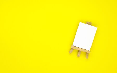 drawing equipment, wooden easel with a blank canvas isolated on a yellow background. background for designers with space for textの写真素材