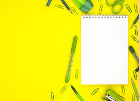 white blank Notepad with green school stationery isolated on a yellow background, top view. background for designers with space for text. online learningの写真素材