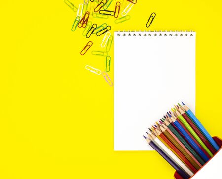 a white blank Notepad in the center and colored pencils with scattered scrapers in the corners. stationery for school preparation. background for designers with space for text. interactive learningの写真素材