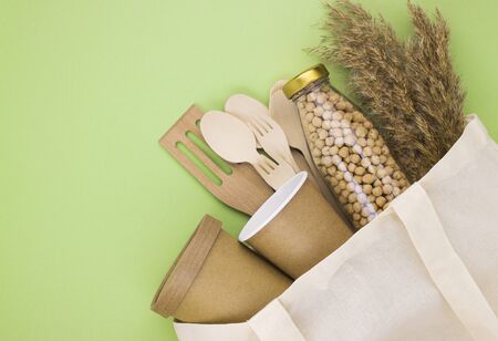 eco dishes and eco containers for food and drinks in a linen eco bag on a light green background with a copy space. preserving the cleanliness of the environment, taking care of nature, waste disposalの写真素材