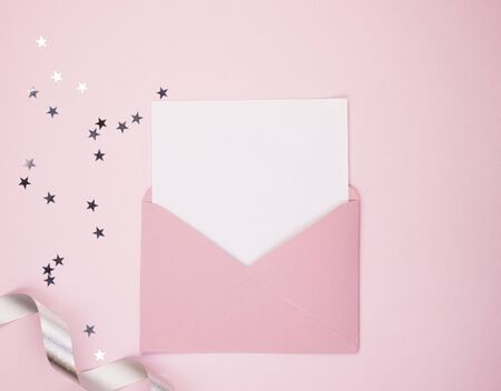 Open pink envelope, with a blank sheet of white paper, space for text. On a pink background, shiny confetti stars. Concept of women's holidays and Valentine's Dayの写真素材