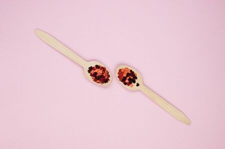 Eco-friendly biodegradable compostable wooden spoons on a soft pink background. Red confetti hearts on spoons. Background for the holidaysの写真素材