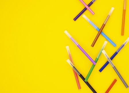 colorful markers are scattered on a yellow background. educational school supplies. stationery for...