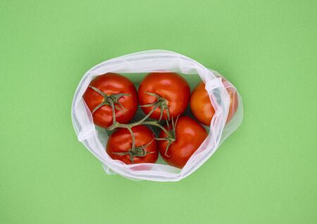 ECO-natural bags with fruits and vegetables, red tomatoes on a light green background, space for...