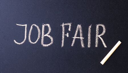 text job fair written in white chalk on a black surface. the concept of job search. invitation to an interviewの写真素材