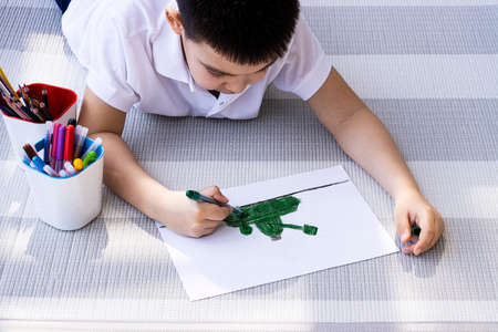The child draws with colored markers. hands of a child drawing on paper, close-upの写真素材