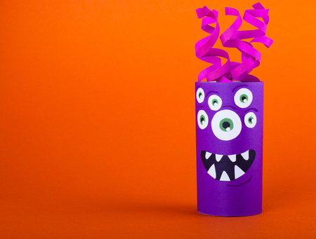 purple scary monster made from a roll of toilet paper on orange background. cute handmade craft monstersの写真素材