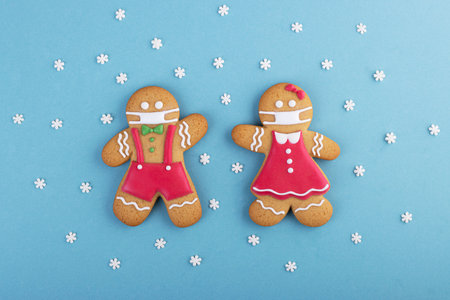 Gingerbread man with a mask on his face on a blue background. Creative gingerbread in the concept of COVID-19 syndromeの写真素材