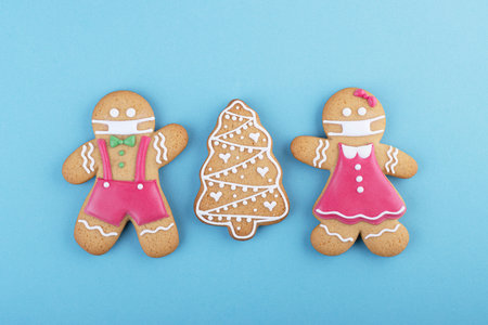 gingerbread man in a ginger cookie face mask iced sugar decoration on a blue background, minimal seasonal Pandemic Winter holiday cardの写真素材
