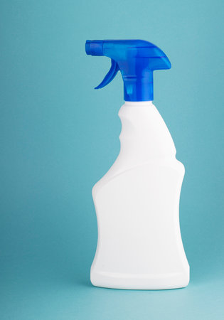 Window cleaner in a white plastic bottle with a spray on a blue white background. the concept of cleaning and cleanlinessの写真素材