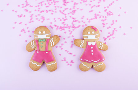 gingerbread men boy and girl in a ginger cookie face mask iced sugar decoration on a pink...