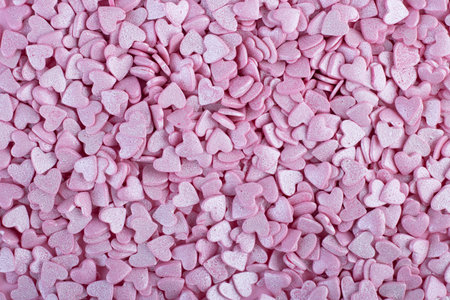 the pink surface is covered with lots of heart-shaped pink confetti as a romantic background...