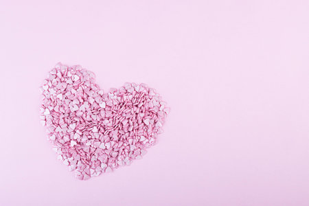 Hundreds of tiny pink heart-shaped hearts lie in the shape of a large heart as a symbol of romantic...