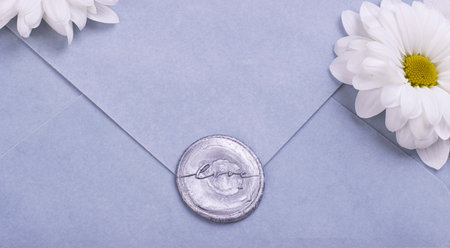 Blue handmade paper envelope with love wax seal, white flowers on the background. love note for...
