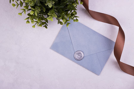 Blue handmade paper envelope with love wax seal, green plant in the background. love note for...