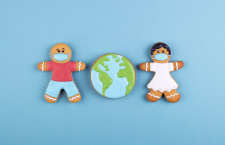 two gingerbread man medics in a mask girl and boy, gingerbread planet earth in the middle. the coronavirus pandemic. thank you to the medical staff, the doctor, the nursesの写真素材