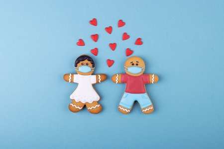 Gingerbread boy and girl in medical masks, lots of little red hearts. Valentine's day during the coronavirus pandemicの写真素材