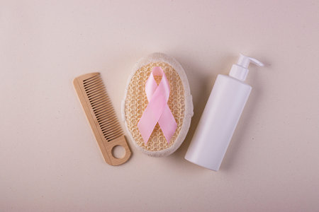 Women's body care products and a pink ribbon, a symbol of the fight against cancer, top view....
