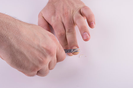 Men's hands cut their fingernails with scissors on a white background. Men's manicure, hand careの写真素材