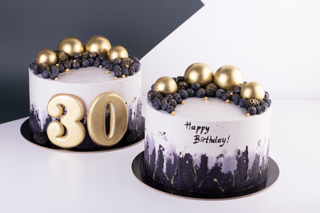 Festive black and white cakes 30 years old with golden balls and dark berries. birthday and anniversary cakeの写真素材