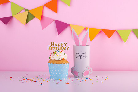 cute rabbit made of handmade paper with a small cake and the inscription happy birthday. celebration, celebration with confettiの写真素材