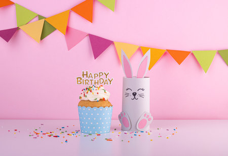 cute rabbit made of handmade paper with a small cake and the inscription happy birthday. celebration, celebration with confettiの写真素材