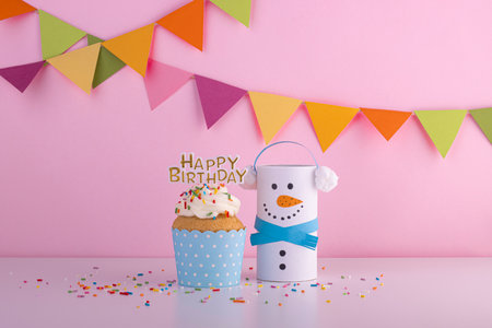 Birthday cupcake with a fun handmade paper snowman. Festive background for birthday partyの写真素材