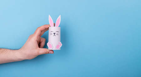 paper Easter bunny in hand on a blue backgroundの写真素材