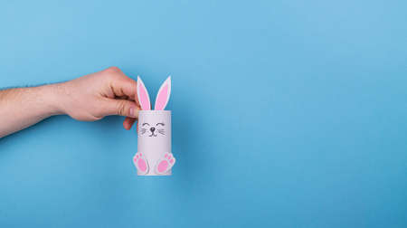 paper Easter bunny in hand on a blue backgroundの写真素材