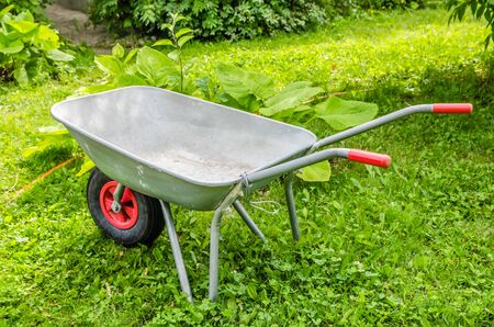 garden trolley with red handles and wheels stands on the grassの写真素材