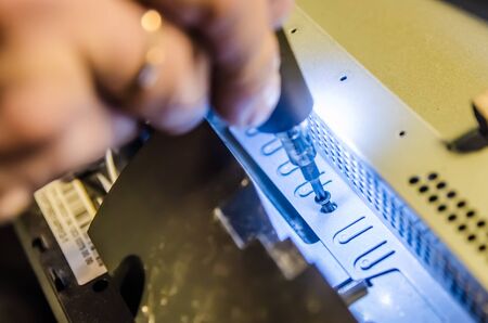 man unspins the cover of the computer of the monoblock with a screwdriver with backlightの写真素材