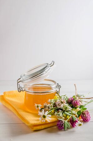 fresh floral honey in the jar and flowers on a white background with a copy spaceの写真素材