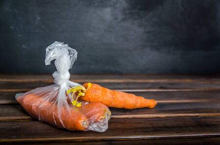 concept plastic free carrots in a plastic bag on a brown background with copy spaceの写真素材
