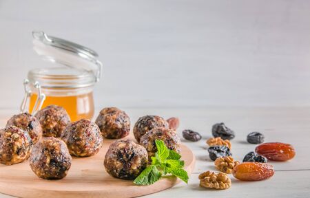 vegetarian food, homemade energy balls of walnuts, dates, prunes, cranberries and honey on white background with copy spaceの写真素材