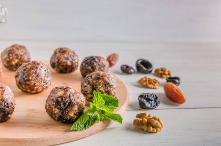 vegetarian food, homemade energy balls of walnuts, dates, prunes, cranberries and honey on white...