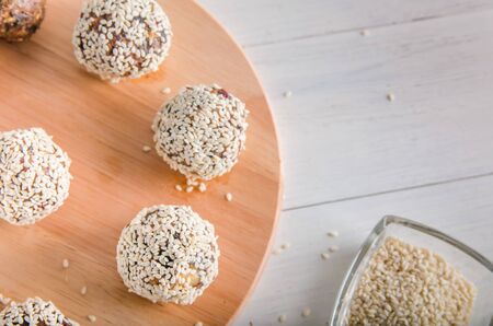 vegetarian food, homemade energy balls of walnuts, dates, prunes, cranberries and honey with sesame on white backgroundの写真素材