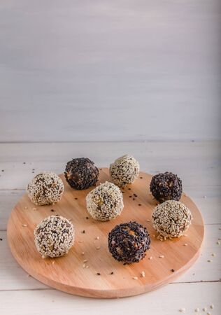 vegetarian food, homemade energy balls of walnuts, dates, prunes, cranberries and honey with white and black sesame on white background. Copy spaceの写真素材