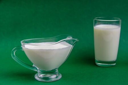 dairy products fresh sour cream and a glass of milk on a green background with copy spaceの写真素材