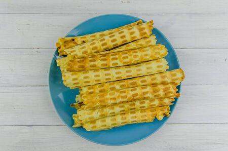 homemade waffle tubes on a blue plate on white backgroundの写真素材