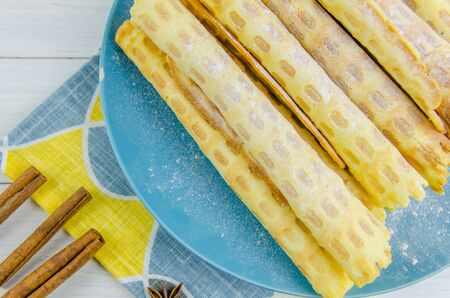 homemade waffle tubes on a blue plate on white backgroundの写真素材