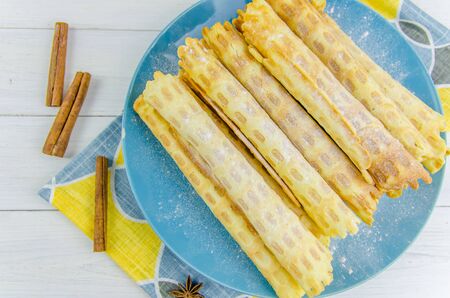 homemade waffle tubes on a blue plate on white backgroundの写真素材
