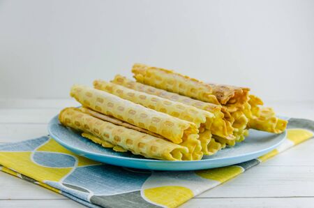 homemade waffle tubes on a blue plate on white backgroundの写真素材