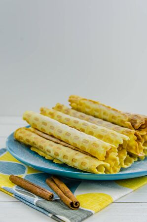 homemade waffle tubes on a blue plate on white background with copy spaceの写真素材