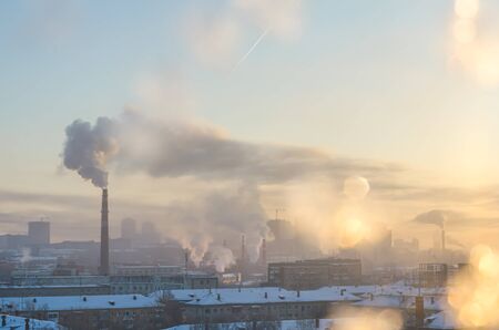 View of the industrial city in winter. glare of the sun, snow