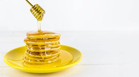 Pancake with honey flows down a stack of pancakes. Honey dripping down a pancake stack. Banner sweet food, dessert, copy spaceの写真素材