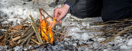 banner bonfire in the forest in winter. Man lights a fire Hiking